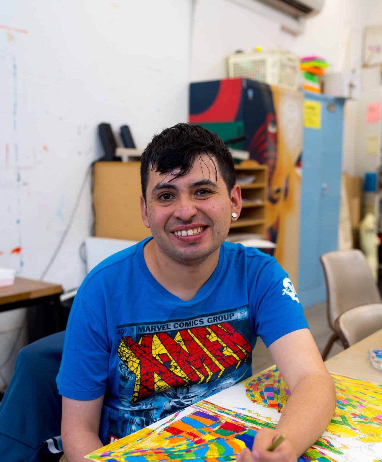 Image of Diego smiling with his artwork in front of him.